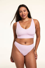 On a light studio backdrop, Alana wears the Bliss Bralette in Retro Lilac with matching underwear. The wireless bralette features a scoop neckline, smoothing sides, and soft microfiber fabric. 