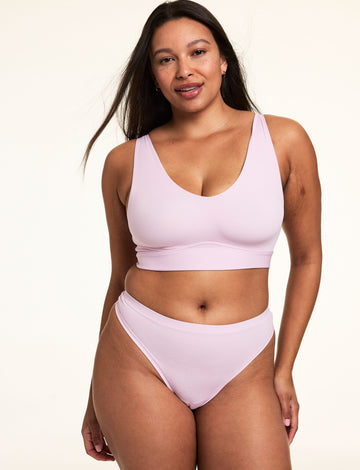 On a light studio backdrop, Alana wears the Bliss Bralette in Retro Lilac with matching underwear. The wireless bralette features a scoop neckline, smoothing sides, and soft microfiber fabric. 