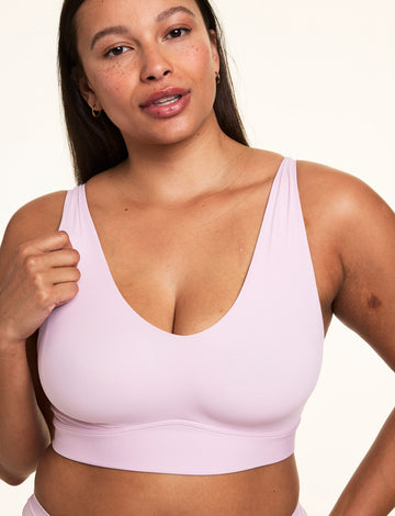 On a light studio backdrop, Alana wears the Bliss Bralette in Retro Lilac, highlighting the scoop neckline, wireless support, and smooth microfiber fabric. sizing: Alana wears a size Large