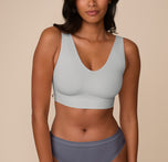 Victoria wears the Bliss Bralette in Stormy, a soft grayish-blue hue. The bralette features a deep V-neckline and wide shoulder straps, offering light support and a sleek, modern look. sizing: Victoria wears size Medium