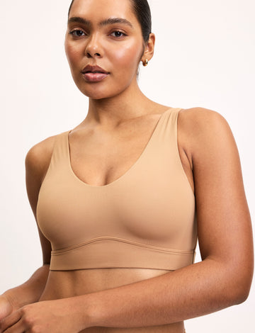 On a light studio backdrop, Amber wears the Bliss Bralette in Tan with matching underwear. The wireless bralette features a scoop neckline, smoothing sides, and soft microfiber fabric.  sizing: Amber wears size Large
