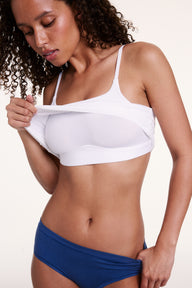 Against a neutral backdrop, Courtney lifts the hem of the Bliss Cami in White to reveal the built-in wireless support. The thin adjustable straps and soft microfiber fabric provide smooth, everyday comfort.