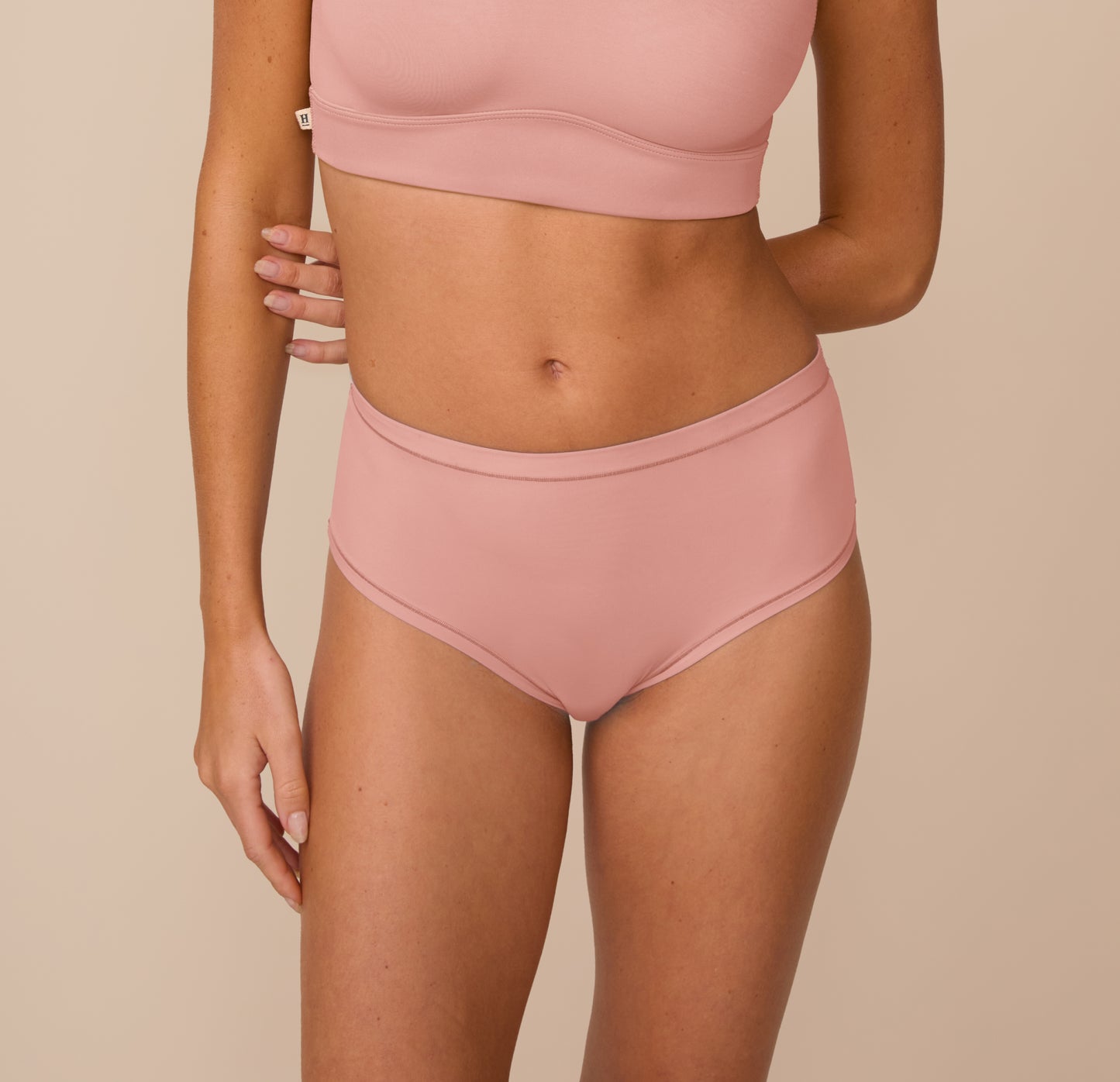 sizClose-up of Freya wearing the Bliss Highwaist Brief in Dusty Rose. The brief sits at the natural waist and features Harper Wilde’s soft microfiber fabric with elastic-free edges for all-day comfort. sizing: Freya wears size Small
