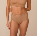 Freya wearing the Bliss Highwaist Brief in Tan. The comfort seams and high rise waistband are emphasized. sizing: Freya wears size Small