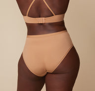 Back view of Akesha wearing the Bliss Highwaist Brief and Base T-Shirt Bra in Tan. The high rise waistband and full coverage back are emphasized.