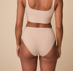 A rear view of Ally modeling the Bliss Highwaist Brief in Beige, showcasing the full-coverage design and comfortable construction for a smooth look under clothing.