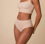 Ally wearing the Bliss Highwaist Brief in Beige, captured from a slight angle to highlight the curve-hugging fit and soft, stretchy fabric.