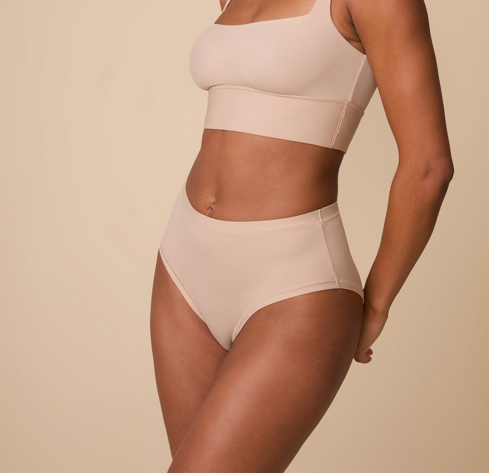Ally wearing the Bliss Highwaist Brief in Beige, captured from a slight angle to highlight the curve-hugging fit and soft, stretchy fabric.