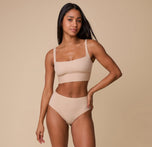 Ally wearing the Bliss Highwaist Brief in Beige, paired with the matching Bliss Square Neck Bralette. She stands confidently, showcasing the sleek and modern design of the brief.