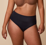 A close-up of India wearing the Bliss Highwaist Brief in Black. The high-rise fit sits smoothly at the waist, offering full coverage with a sleek, comfortable design. sizing: India wears size Large