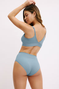 Three-quarter back view on a white studio backdrop of Darion wearing the Bliss Highwaist brief in Poolside, focusing on the smooth back coverage, high waist, and lightweight microfiber fabric.