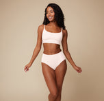 Ally faces the camera wearing the Bliss Scoop Bralette and Bliss Highwaist Brief in Quartz.