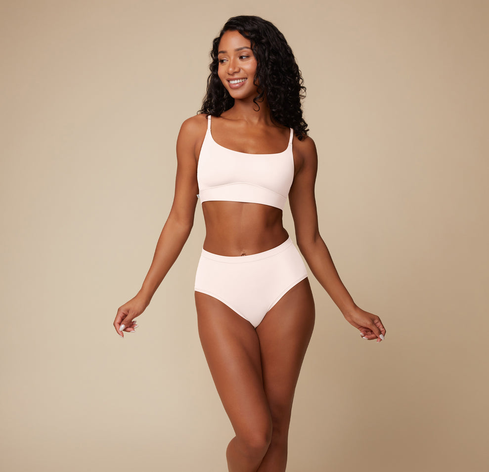 Ally faces the camera wearing the Bliss Scoop Bralette and Bliss Highwaist Brief in Quartz.