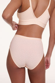 In a studio back view, a model wears the Bliss Highwaist Brief in Champagne Fizz with the Bliss Triangle Bralette in Champagne Fizz, showing the high-rise waistband, full back coverage, and soft microfiber fabric with a subtle dotted pattern.