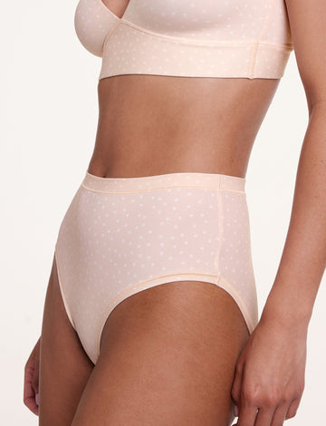 In a studio side view, a model wears the Bliss Highwaist Brief in Champagne Fizz with the Bliss Triangle Bralette in Champagne Fizz, highlighting the high-rise waistband, smooth leg openings, and soft microfiber fabric with a subtle dotted pattern. sizing: Courtney wears size Small