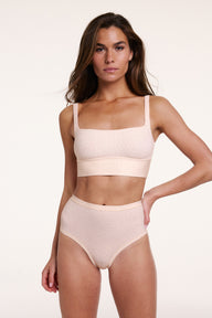 In a studio setting, Gianna wears the Bliss Highwaist Brief in Champagne Fizz with the Bliss Square Neck Bralette in Champagne Fizz, highlighting the high-rise waistband, full coverage design, and soft microfiber fabric with a subtle dotted pattern.