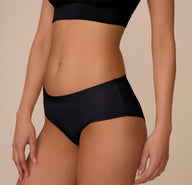 Angled side view of Marcela wearing the Bliss Hiphugger in Black. The image highlights the sleek, seamless construction and flattering, stay-put waistband.