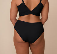 Back view of Zarria modeling the Bliss Hiphugger in Black. The image highlights the high-quality microfiber fabric and full back coverage.