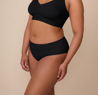 Angled side view of Zarria in the Bliss Hiphugger in Black. The wide-cut leg openings and ultra-soft finish are visible, emphasizing all-day comfort.