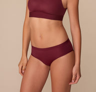 Side angle of Alexis modeling the Bliss Hiphugger in Bordeaux, showcasing the contoured fit and ultra-soft stretch fabric.