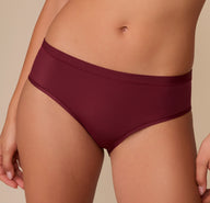Close-up of the Bliss Hiphugger in Bordeaux on Alexis, emphasizing the smooth waistband, flat seams, and modern silhouette.