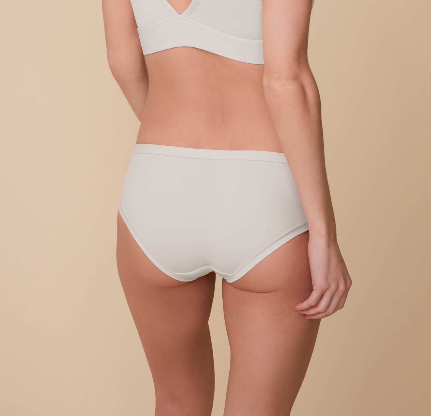 Back view of Gracie wearing the Bliss Hiphugger in Frost, highlighting the full coverage and smoothing microfiber fabric with a cotton gusset for breathable comfort.