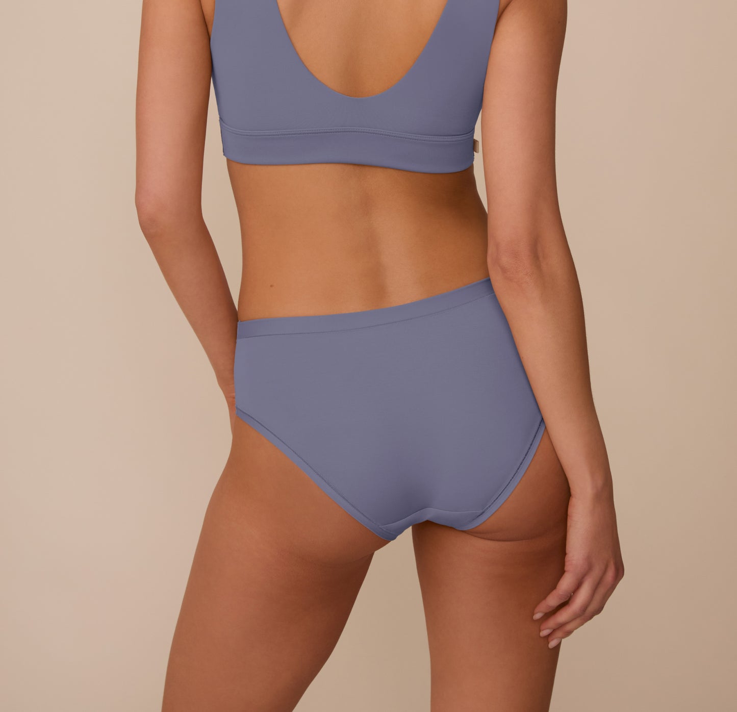 Back view of Marcela wearing the Bliss Hiphugger in Steel. The image focuses on the smooth, full coverage and the dig-free fit across the back.