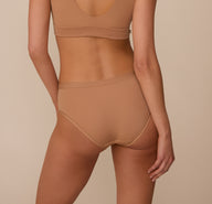 Back view of Marcela in the Bliss Hiphugger in Tan, highlighting the full rear coverage and minimal seam construction that creates a no-show effect under clothing.