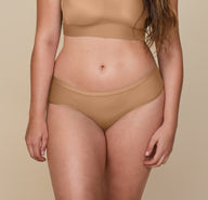 Close-up of a model wearing the Bliss Bralette and Bliss HipHugger in Tan. The focus is on the midsection, highlighting the soft, comfortable fabric and relaxed fit. sizing: Summerlyn wears size Large