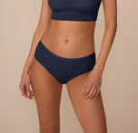 Marcela wears the Bliss Hiphugger in True Blue, shown from the front. The image highlights the mid-rise waistband and smooth front panel made from soft, stretchy microfiber. sizing: Marcela wears size Small