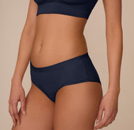 Side profile of Marcela in the Bliss Hiphugger in True Blue. The image highlights the smooth leg openings and seamless construction designed for invisible wear under clothes.
