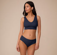 Marcela wears the Bliss Hiphugger and matching Bliss Bralette in True Blue. The image shows the coordinated set from the front with a focus on comfort and clean lines.