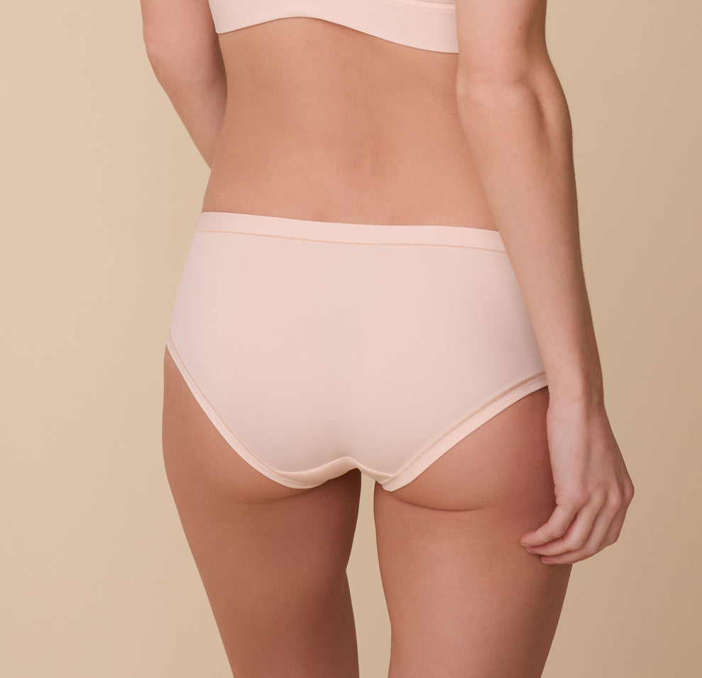 Back view of Gracie wearing the Bliss Hiphugger in Rose. The comfort seams and medium coverage is emphasized.