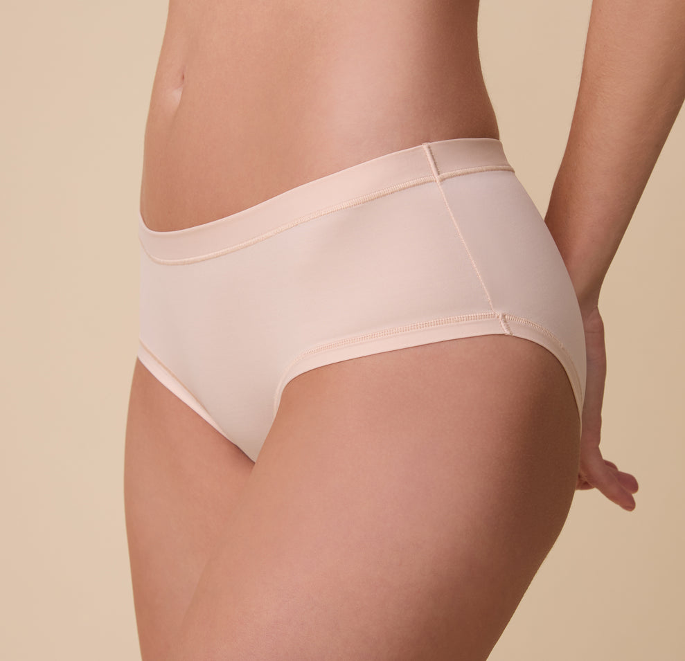 A three quarter angled shot of Gracie wearing the Bliss Hiphugger in Rose. The mid-rise waistband and comfortable fabric is emphasized.