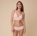 A full body shot of Gracie wearing the Bliss Hiphugger in Rose paired with the matching Bliss Triangle Bralette. The light pink color is emphasized along with the mid-rise waistband.