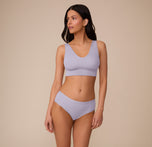 Full-body view of Marcela in the Bliss Hiphugger in Violet and the Bliss Bralette in Violet, posed in a relaxed stance. The set features a coordinated look in a soft lavender tone, emphasizing comfort and simplicity.