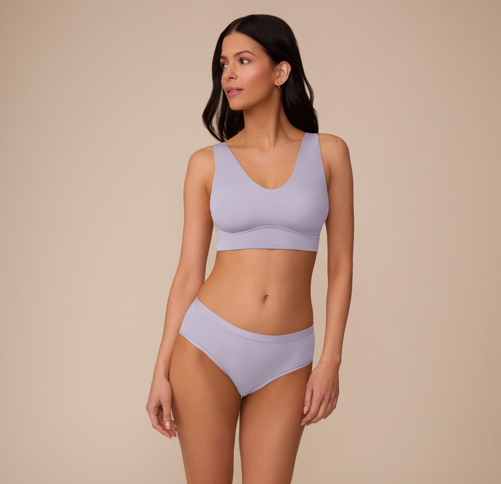 Full-body view of Marcela in the Bliss Hiphugger in Violet and the Bliss Bralette in Violet, posed in a relaxed stance. The set features a coordinated look in a soft lavender tone, emphasizing comfort and simplicity.
