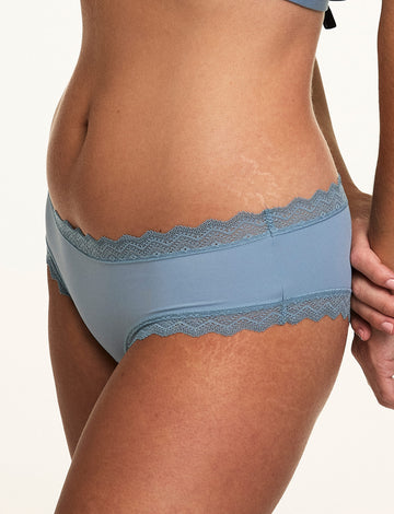 Close-up of Sonnie wearing the Bliss Lace Cheeky in Poolside, highlighting the soft lace waistband, cheeky cut, and smooth microfiber fabric.