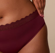 Extreme close-up of the lace waistband and fabric texture on the Bliss Lace Highwaist Brief in Bordeaux, showcasing the stretch and softness of the material.