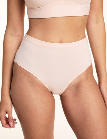 In a studio setting, Laura wears the Bliss Lace Highwaist Brief in Rose, featuring a high-rise silhouette, smooth microfiber fabric, and clean bonded edges with full front coverage.