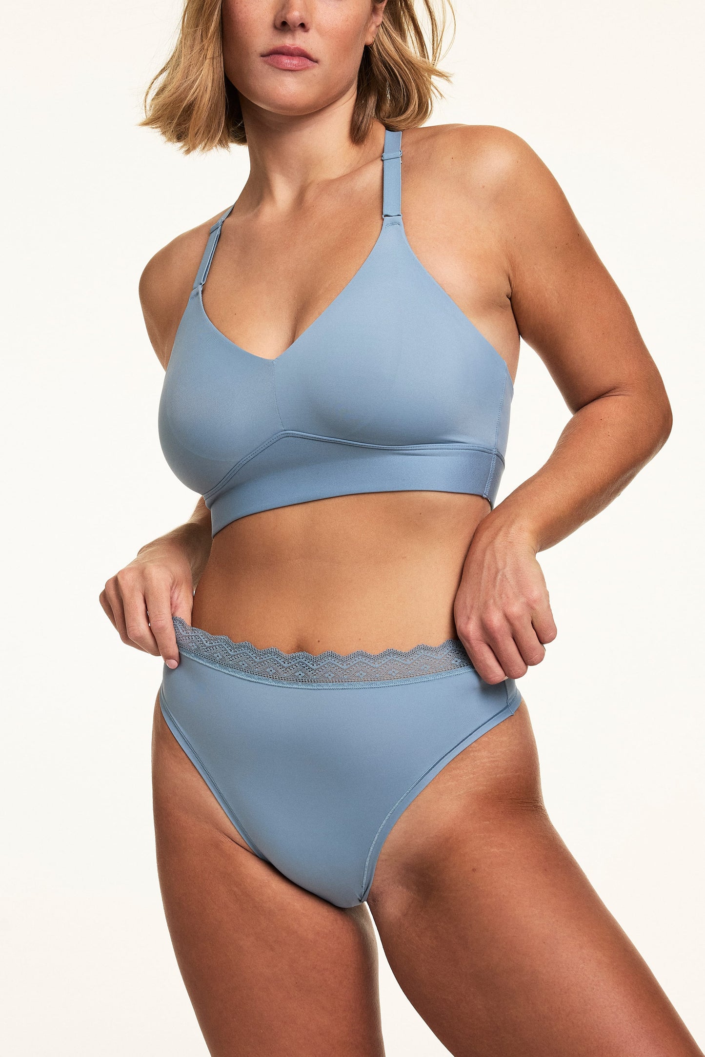 On a white studio backdrop, Sonnie wears the Bliss Lace Highwaist Thong in Poolside with a matching Poolside bralette, showing the high-rise fit and lace waistband detail. sizing: Sonnie wears size Large
