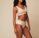 Side view of Ally wearing the Bliss Lace Highwaist Brief in Beige, paired with the Bliss Lace Bralette. The image highlights the high-waisted design and the flattering fit of the brief.