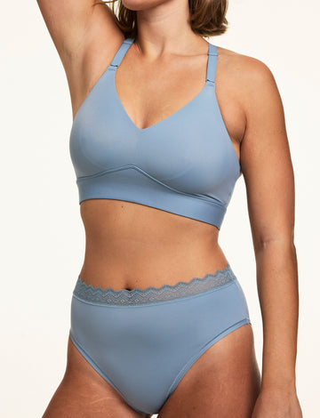 On a white studio backdrop, Sonnie wears the Bliss Lace Highwaist in Poolside with a matching Poolside bralette, highlighting the high-rise silhouette, smooth microfiber fabric, and soft lace waistband.  sizing: Sonnie wears size Large