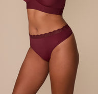 Side view of Victoria in the Bliss Lace Highwaist Thong in Bordeaux. This image showcases the smooth, elastic-free construction and flattering high-rise silhouette.