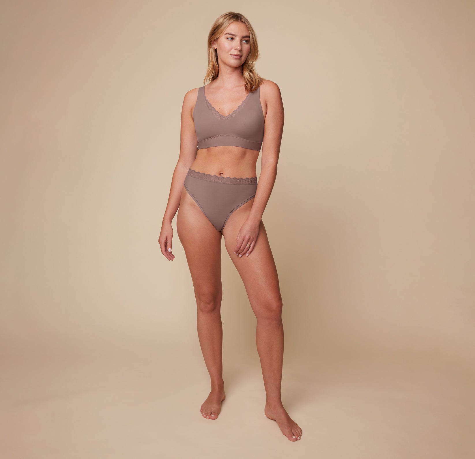 Model Megan wearing the Bliss Lace Thong in Mauve, paired with the matching Bliss Lace Halterneck Bralette. She stands facing forward, highlighting the soft fit of the lace thong and the supportive halterneck bralette.