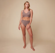 Model Megan wearing the Bliss Lace Thong in Mauve, paired with the matching Bliss Lace Halterneck Bralette. She stands facing forward, highlighting the soft fit of the lace thong and the supportive halterneck bralette.