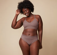 Akesha smiling while wearing the Bliss Lace Halterneck Bralette and matching Bliss Lace Highwaist Brief in Mauve. The image highlights the bralette’s halterneck design and the highwaisted fit of the brief, emphasizing comfort and style.