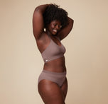 Akesha posing with her arm raised, wearing the Bliss Lace Halterneck Bralette and Bliss Lace Highwaist Brief in Mauve. The image captures a side view, highlighting the comfortable fit of both pieces.