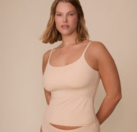 Front view of Sonnie wearing the Bliss Cami in Beige. The cami features a scoop neckline, thin adjustable straps, and a soft, smoothing fit over the torso. sizing: Sonnie wears size Medium