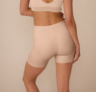 Back view of Marcela wearing the Bliss Under Short in Beige, highlighting the clean finish and comfortable coverage of the mid-thigh length short.